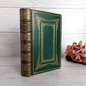 May include: A vintage green leather-bound book with gold-leaf detailing and the title "Rogers's Poetical Works" on the spine.