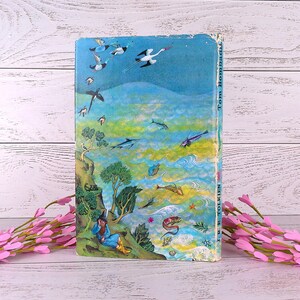 Op de afbeelding: Een vintage boek met een kleurrijke illustratie. De omslag toont een tovenaar, vogels en zeedieren tegen een blauwgroene achtergrond. De titel "Tom Bombadil" en de auteur "J.R.R. Tolkien" zijn zichtbaar op de rug.