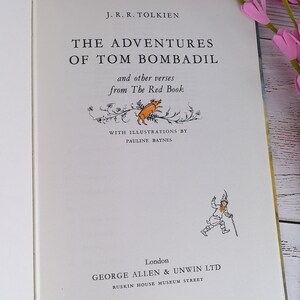 Op de afbeelding: Open boek getiteld "The Adventures of Tom Bombadil" van J.R.R. Tolkien, met illustraties van Pauline Baynes. De kaft bevat tekst en illustraties van een varken en een man met een staf. Het boek is open.