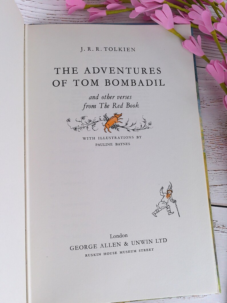 Op de afbeelding: Open boek getiteld "The Adventures of Tom Bombadil" van J.R.R. Tolkien, met illustraties van Pauline Baynes. De kaft bevat tekst en illustraties van een varken en een man met een staf. Het boek is open.