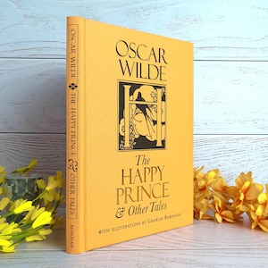 May include: A hardcover book titled "The Happy Prince & Other Tales" by Oscar Wilde. The book has a yellow cover with black text and illustrations. The spine reads "Oscar Wilde" and "The Happy Prince & Other Tales".
