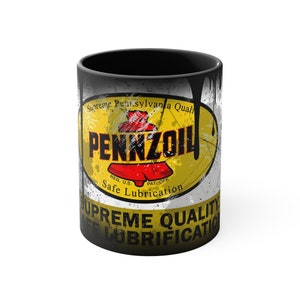 May include: Black ceramic mug featuring a vintage Pennzoil oil can design. The design includes a yellow and red logo with the text "Supreme Pennsylvania Qual", "PENNZOIL", "REG. U.S.", "PAT. OFF.", "Safe Lubrication", and "UPREME QUALITY" in black and white.