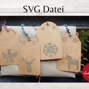 Puede incluir: Cinco etiquetas de regalo de papel marrón con diferentes diseños, incluyendo un copo de nieve, un ciervo, un ángel, un caballo y una estrella. Las etiquetas están atadas con cordel y están en una caja de regalo envuelta en papel marrón. El texto "SVG Datei" está en la parte superior de la imagen.