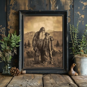 Puede incluir: Una fotograf&iacute;a en sepia de un gran Bigfoot peludo de pie junto a un hombre en un entorno boscoso. El Bigfoot tiene una expresi&oacute;n amigable y una larga barba. El hombre lleva un sombrero y una chaqueta. La fotograf&iacute;a est&aacute; enmarcada en un marco negro.