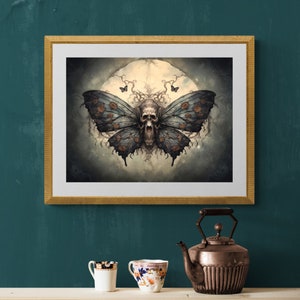 May include: A framed print of a dark, gothic-style illustration of a skull with wings, resembling a butterfly, against a backdrop of a full moon and swirling clouds.
