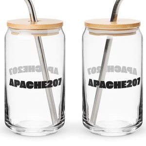 Puede incluir: Dos vasos de vidrio transparentes con tapas de bambú y pajitas de acero inoxidable. Los vasos tienen el texto "APACHE207" impreso en ellos.