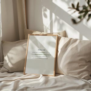 K&ouml;nnte beinhalten: Ein gerahmter Druck mit Text in einem hellen Holzrahmen. Der Druck ist an Kissen und einer Decke angelehnt. Der Text ist in Schwarz und Gr&uuml;n. Der Hintergrund ist in neutralen T&ouml;nen gehalten.