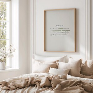 K&ouml;nnte beinhalten: Ein gerahmter Druck mit spanischem Text in einem Schlafzimmer. Der Text hat einen hellgr&uuml;nen Akzent. Der Rahmen ist aus hellem Holz und die Bettw&auml;sche ist beige. Ein Fenster mit wei&szlig;en Blumen ist sichtbar.