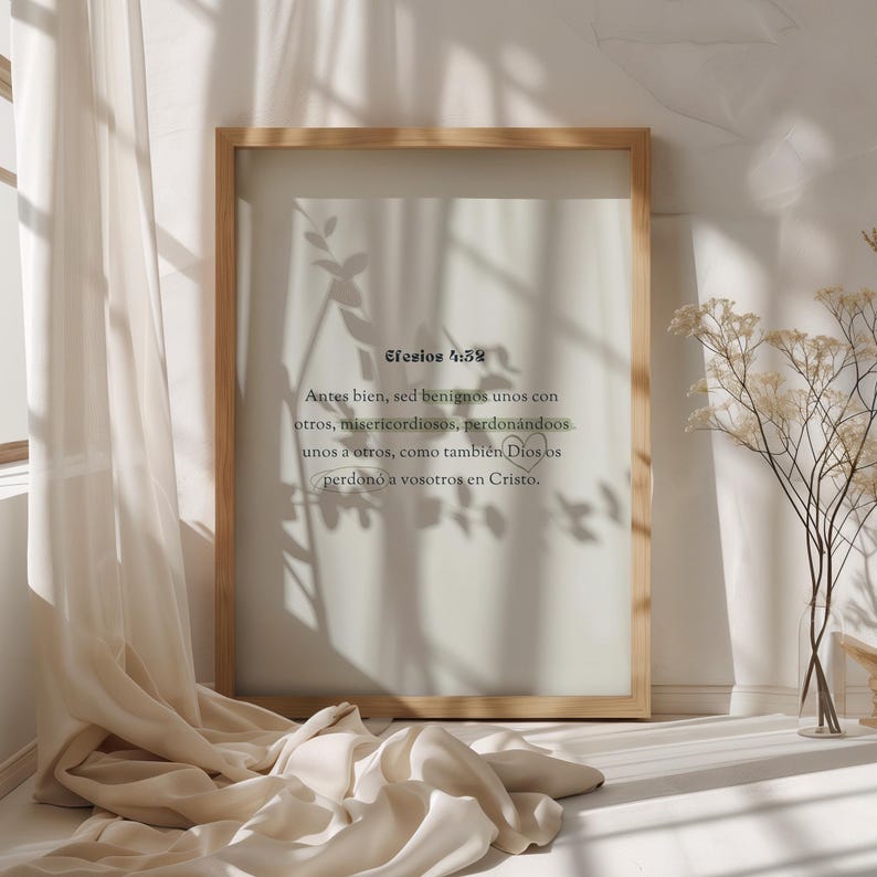 K&ouml;nnte beinhalten: Ein gerahmter Druck mit einem hellen Holzrahmen. Der Druck zeigt Text auf Spanisch mit einem weichen, neutralen Hintergrund. Der Druck lehnt an einer wei&szlig;en Wand, mit einem beigen Vorhang und Trockenblumen im Hintergrund.