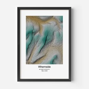 May include: A framed print of a topographic map of Whernside, a mountain in the Yorkshire Dales, England. The map shows the elevation contours of the mountain in shades of green, brown, and white. The coordinates and elevation of Whernside are listed below the map.