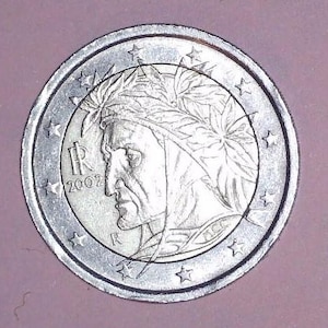 Puede incluir: Una moneda de 2 euros de plata con el perfil de un hombre con una corona de laurel. La moneda tiene el año 2002 y la letra "R". La moneda está rodeada de estrellas.