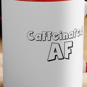 May include: White ceramic mug with a red rim and handle. The mug has black text that reads "Caffeinated AF".