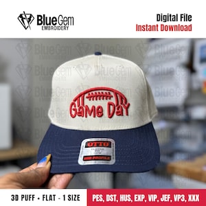 May include: A beige and navy blue baseball cap with a red football and the words "Game Day" embroidered on the front. The cap has a flat brim and a mid-profile fit.