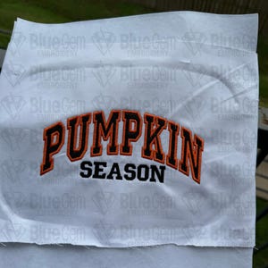 May include: White fabric with an orange and black embroidered design that says "Pumpkin Season".