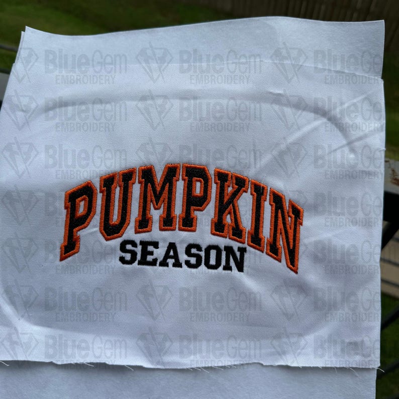 May include: White fabric with an orange and black embroidered design that says "Pumpkin Season".