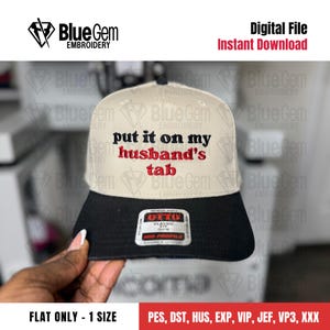 Könnte beinhalten: Beige-schwarze Baseballkappe mit dem Text "put it on my husband's tab" in Rot und Schwarz gestickt. Die Kappe hat einen flachen Schirm und eine mittlere Passform. Die Marke "OTTO" ist auf der Vorderseite sichtbar.