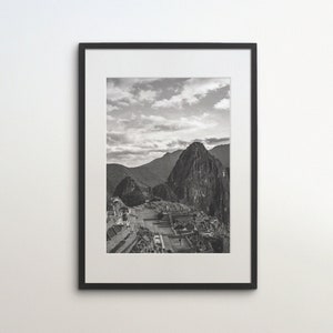 May include: A black and white photograph of a mountain range with a city in the foreground. The photo is framed in a black frame.