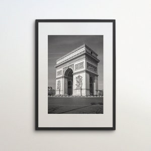 Op de afbeelding: Een zwart-witfoto van de Arc de Triomphe in Parijs, Frankrijk. De boog is een beroemd monument en is gemaakt van steen. De foto is genomen vanuit een lage hoek, waardoor de boog erg groot lijkt.