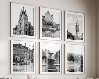 May include: A living room with a white couch, a coffee table, and a white ottoman. There are six black and white framed photos on the wall, and a window with a view of trees.