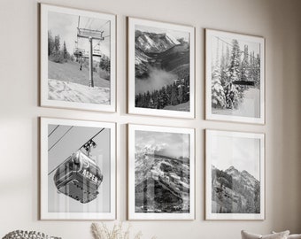 May include: Six framed black and white landscape prints of mountain scenes and ski lifts hang on a wall above a beige sofa. The prints feature snowy mountains and ski lift infrastructure. The word "Aspen" is visible on one of the gondolas.