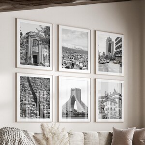 May include: A living room interior with a white couch and a coffee table. The walls are decorated with black and white framed photographs of cityscapes.