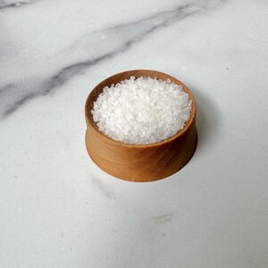 Puede incluir: Un peque&ntilde;o cuenco de madera lleno de cristales de sal blanca.