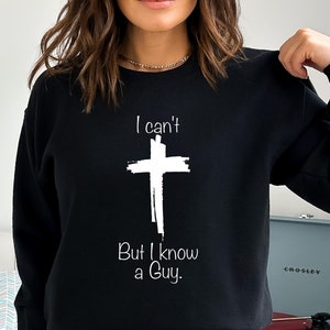 May include: Black sweatshirt with a white cross and the text "I can't But I know a Guy."