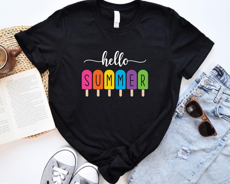 May include: Black t-shirt with the words "hello SUMMER" in white script above a row of colorful popsicle graphics. The popsicles are pink, orange, yellow, blue, and green. The shirt is paired with blue jeans, sunglasses, and sneakers.