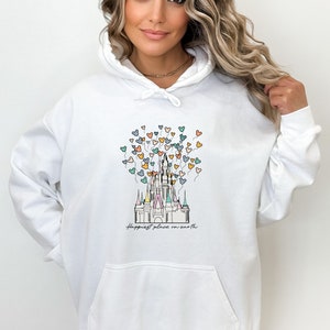 May include: White hoodie with a graphic of Cinderella's castle with colorful Mickey Mouse balloons and the text "Happiest place on earth".
