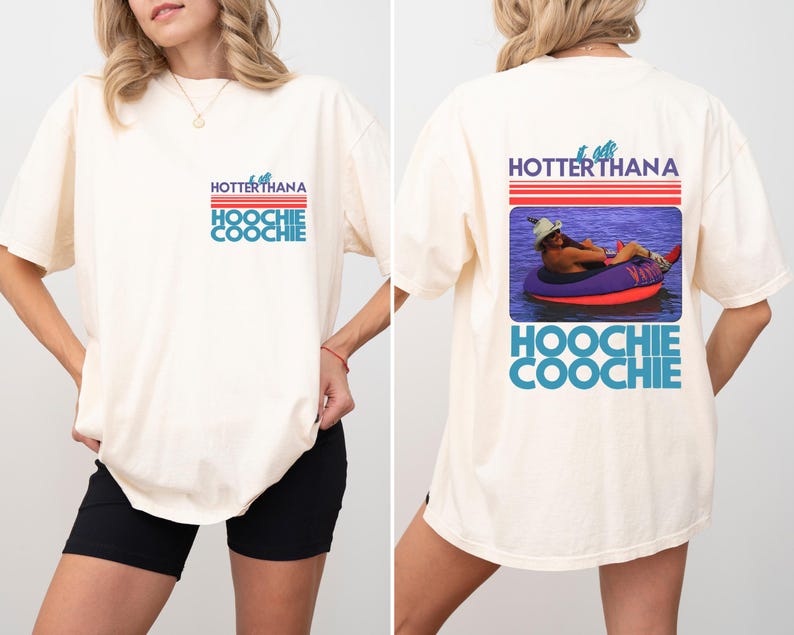 May include: Cream-colored t-shirt with the text "HOTTERTHANA HOOCHIE COOCHIE" in red, blue, and white. The back of the shirt features a graphic of a person in a tube on the water. The shirt is a casual, oversized fit.