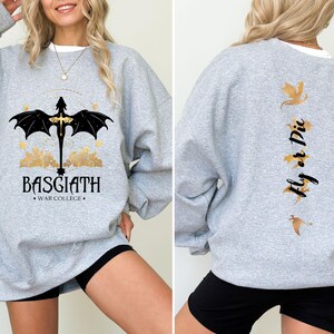 May include: A gray sweatshirt with a black dragon graphic on the front and the text "BASGIATH WAR COLLEGE". The back of the sweatshirt has a gold dragon graphic and the text "Fly or Die".