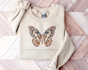 May include: A beige sweatshirt with a butterfly graphic and the text "For I know the plans I have for you Jeremiah 29:11".