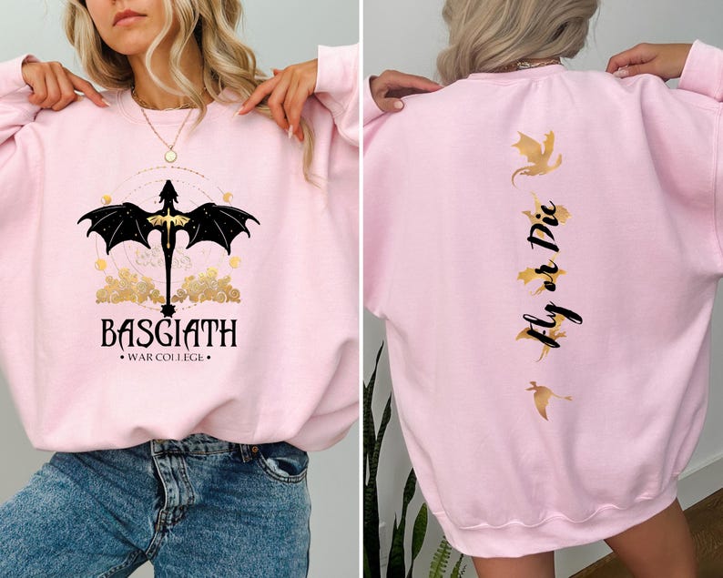 May include: Pink sweatshirt with a black dragon graphic on the front and the text "BASGIATH WAR COLLEGE" and the text "Fly or Die" with gold dragon graphics on the back.
