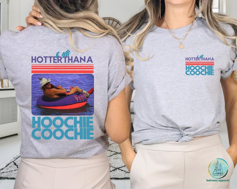 May include: A light gray t-shirt with the text "HOTTER THANA HOOCHIE COOCHIE" in blue and red. The shirt features a graphic of a person in a tube on the water. The same design is on the front and back of the shirt.