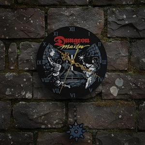 May include: A round wall clock featuring the Dungeon Master logo and a pixelated fantasy dungeon scene with Roman numerals. The clock has ornate gold-colored hands and a hanging pendulum shaped like a spiked mace attached by a small black chain.