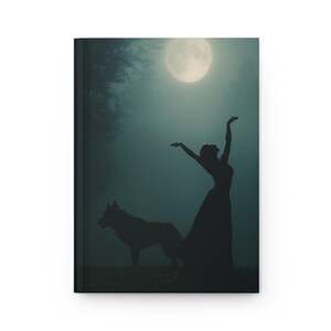 Könnte beinhalten: Ein Notizbuch mit einer Silhouette einer Frau mit ausgestreckten Armen, einem Wolf und einem Vollmond in einer dunklen, atmosphärischen Umgebung. Der Einband ist dunkel und hat eine matte Oberfläche.