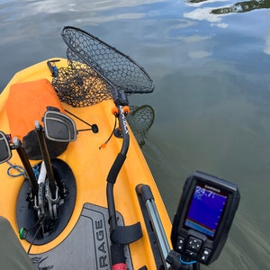 May include: A yellow kayak with a black fishing net, a black and gray fish finder with the text "GARMIN 24.71" on the screen, and the word "MIRAGE" printed on the kayak.