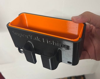 Puede incluir: Una caja de almacenamiento de plástico negra con un interior naranja. La caja tiene el texto "SuperYak Fishing" impreso en la parte delantera.