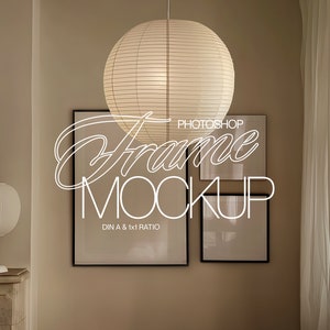May include: A mockup of two picture frames with black frames and white mats hanging on a beige wall. The frames are labeled "DIN A & 1x1 RATIO" and "PHOTOSHOP Frame MOCKUP". A white lamp with a round shade is on a white marble surface in the foreground.