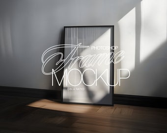 May include: A black frame mockup with the text "Photoshop Frame Mockup DIN A Ratio" in white text. The frame is standing on a wooden floor with a shadow cast from a window.