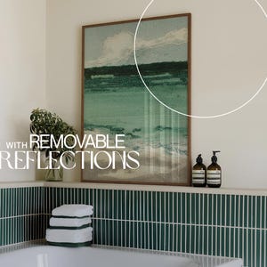 May include: A bathroom with green tile, a white bathtub, and a framed print of a seascape. The print has the text "WITH REMOVABLE REFLECTIONS" on it. There are two bottles of liquid soap on a shelf above the bathtub.