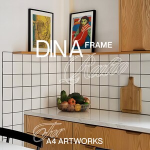 May include: A white tiled kitchen with two framed pictures hanging on the wall. The pictures are both black framed and have colourful artwork inside. The text "DINA FRAME Ratio for A4 ARTWORKS" is written in white on the image.