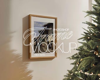 May include: A wooden frame with a picture of a building with a blue sky and white clouds. The frame is on a white wall with a Christmas tree in the background.
