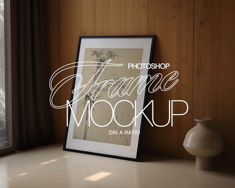 May include: A black framed picture with a black and white image of bamboo plants. The frame is sitting on a light brown surface in front of a wood wall. The text "PHOTOSHOP Frame MOCKUP DIN A RATIO" is written in white on the image.