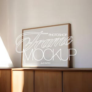 May include: A brown wooden frame with a white mat and a white background. The frame is sitting on a wooden cabinet. The text "Photoshop Frame Mockup 4x5 Ratio" is written in white on the frame.
