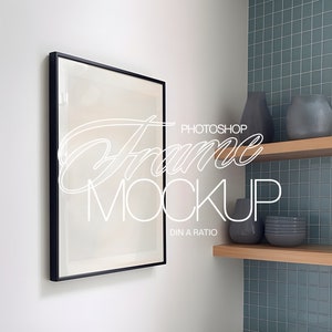May include: A black framed picture mockup hanging on a white wall, with a shelf above it containing a gray vase and a stack of gray bowls. The wall behind the shelf is tiled in a light blue color.
