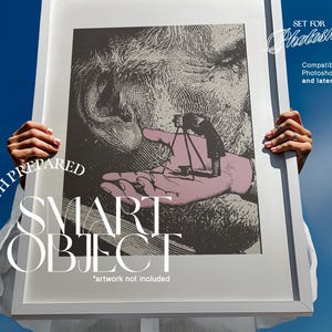 May include: A framed artwork with a black and white illustration of a face and a hand holding a miniature camera. The frame is held against a blue sky. Text on the frame reads "WITH PREPARED SMART OBJECT" and "SET FOR Photoshop".