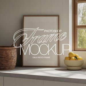 May include: A mockup featuring a framed print, a woven basket, and a bowl of lemons. The frame is rectangular with a light wood finish. The text "Photoshop Frame Mockup" is overlaid on the image. A window with natural light is in the background.