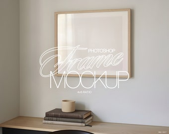 May include: A light wood frame mockup with a 4x5 ratio, hanging on a white wall above a wooden desk. A stack of books and a ceramic cup are on the desk.