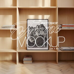 May include: A black and white photo of a mountain range is framed and displayed on a wooden shelf. The shelf is part of a larger wooden bookcase with multiple shelves. The photo is titled "PHOTOSHOP Frame Mockup DIN A RATIO".